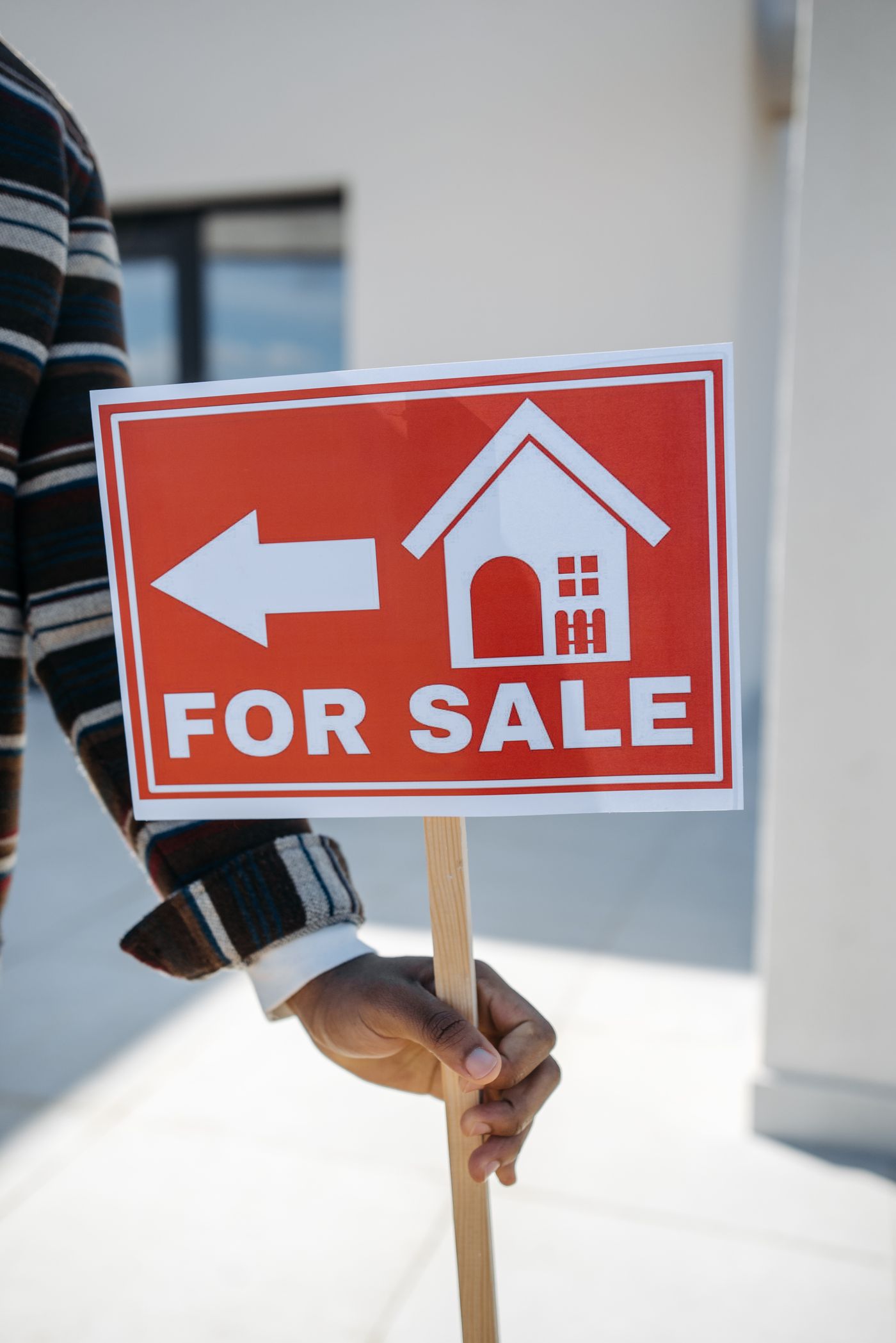 Panneau À vendre tenu à la main devant un bien immobilier